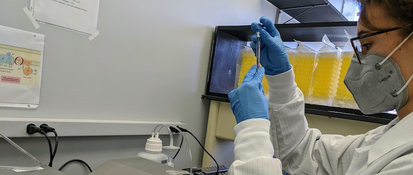 Researcher concentrates on a vial in the lab