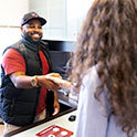 A black male advisor shakes the hand of his student while smiling. 