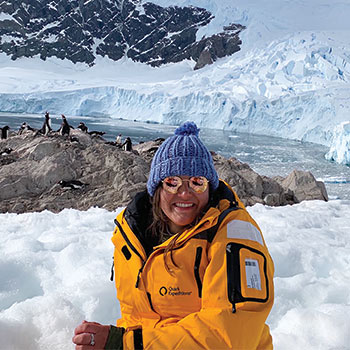 Graduate student in winter gear sitting outside in the snow on a research trip.