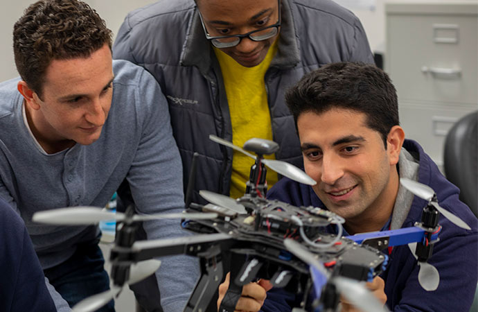 People gathered around inspecting a drone.