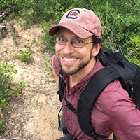 photo of man with glasses on and a garnet shirt 