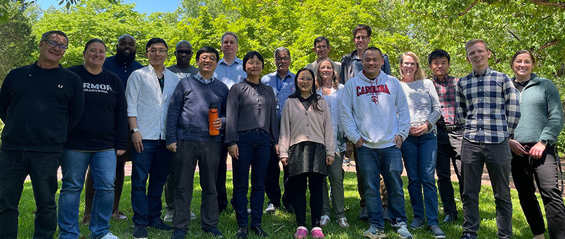 a group of men and women smiling outside at a picnic