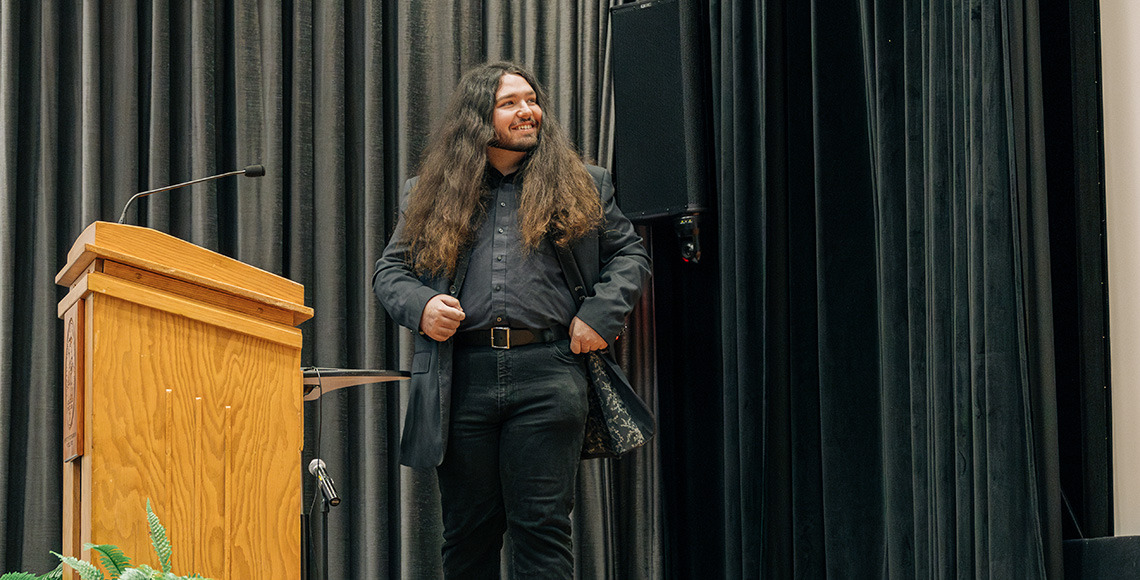 Male student standing on stage and smiling