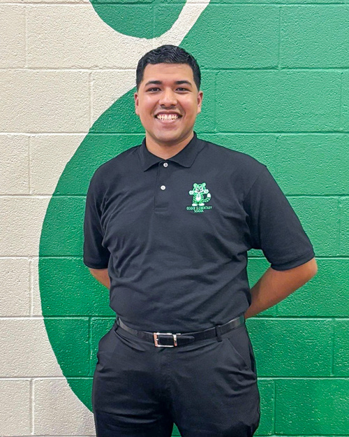 Alvarado smiling in front of a white and green painted wall.