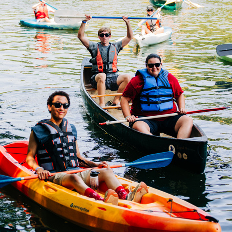 Three students floating down the river during First-Year Flotilla.