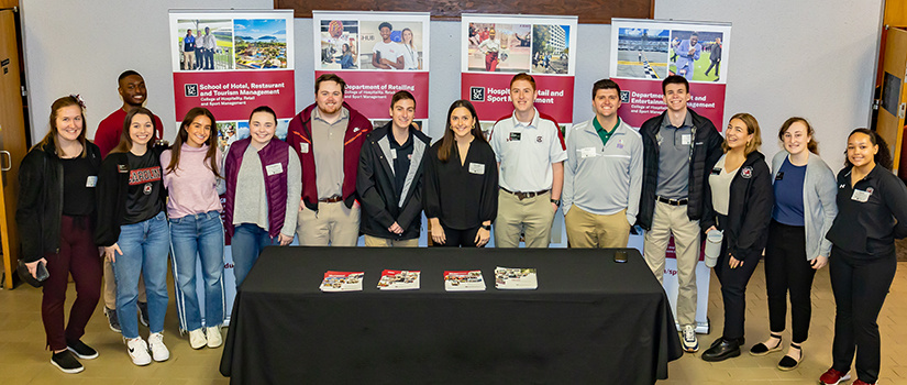 Fourteen students pose for a photo together at Admitted Student Day in front of Belk Auditorium.