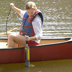 Woman in kayak pulling a tube out of the water