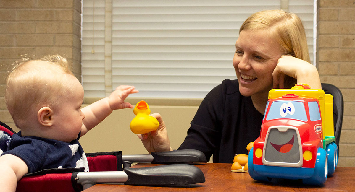 Researcher playing with a baby at a table. 